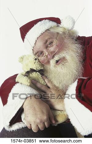 Stock Image - Portrait of Santa Claus hugging a teddy bear. Fotosearch