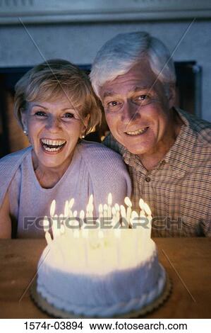 Picture - Senior couple blowing out candles on a cake. Fotosearch