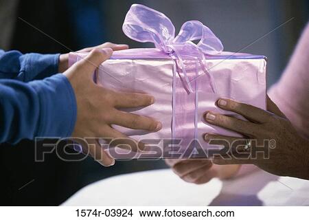 Two people holding a wrapped gift View Large Photo Image Picture - Two people holding a wrapped gift. Fotosearch