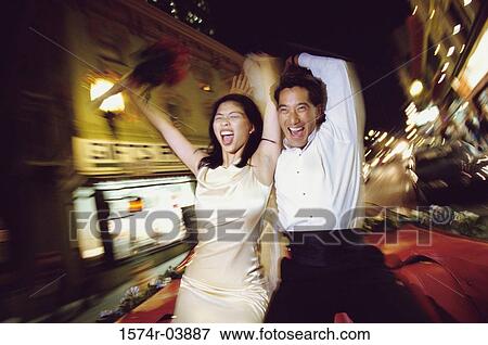 Young couple sitting on the hood of a moving car View Large Photo Image Stock Photo - Young couple sitting on the hood of a moving car. Fotosearch