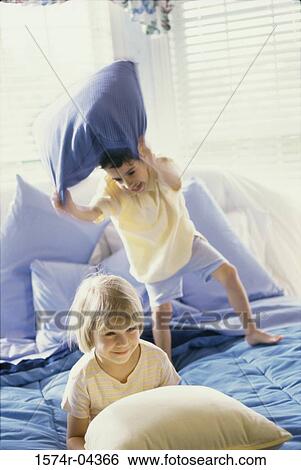 Boy and a girl having a pillow fight on a bed View Large Photo Image Stock Photograph - Boy and a girl having a pillow fight on a bed. Fotosearch