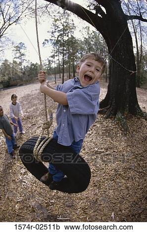 Boy swinging on a tire swing View Large Photo Image Stock Image - Boy swinging on a tire swing. Fotosearch