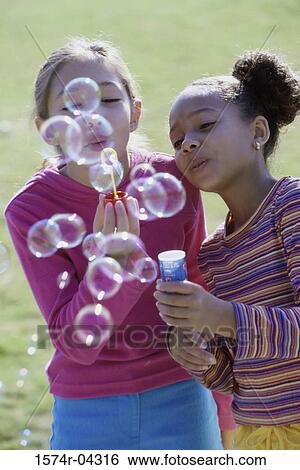 Close-up of two girls blowing bubbles with a bubble wand View Large Photo Image Stock Photograph - Close-up of two girls blowing bubbles with a bubble wand. Fotosearch