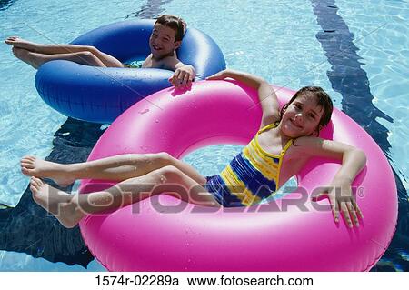 High angle view of a boy and a girl lying on inflatable rings in a swimming pool View Large Photo Image Stock Image - High angle view of a boy and a girl lying on inflatable rings in a swimming pool. Fotosearch