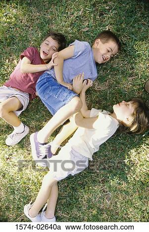 Stock Image - High angle view of a girl and two boys playing in a park. Fotosearch