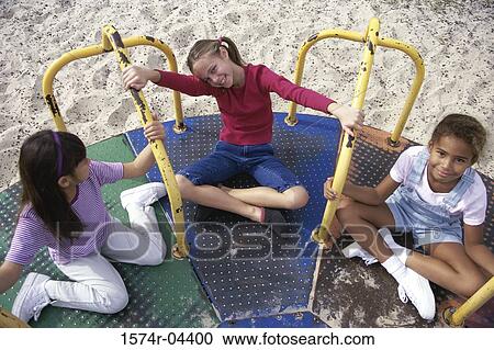 High angle view of three girls playing on a merry-go-round View Large Photo Image Stock Image - High angle view of three girls playing on a merry-go-round. Fotosearch