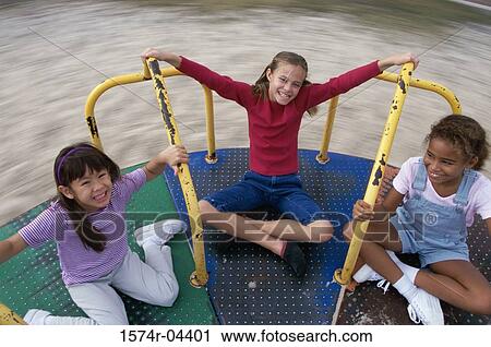 High angle view of three girls playing on a merry-go-round View Large Photo Image Stock Image - High angle view of three girls playing on a merry-go-round. Fotosearch