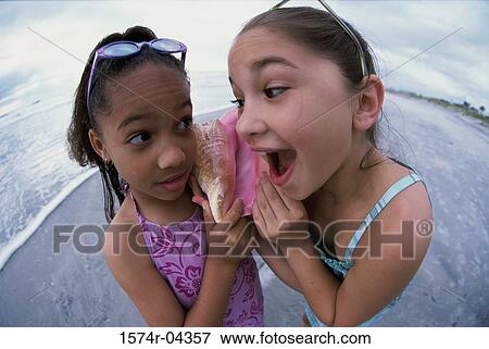 High angle view of two girls holding a conch shell View Large Photo Image Stock Photo - High angle view of two girls holding a conch shell. Fotosearch