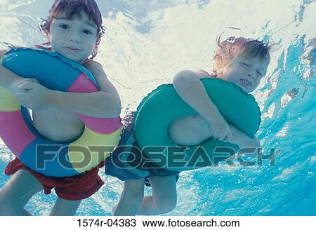 Low angle view of a boy and a girl lying on inflatable rings in a swimming pool View Large Photo Image Stock Image - Low angle view of a boy and a girl lying on inflatable rings in a swimming pool. Fotosearch