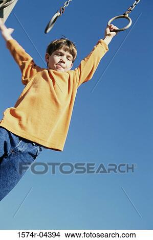 Picture - Low angle view of a boy hanging from a jungle gym. Fotosearch