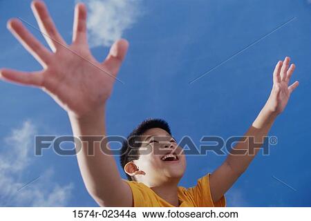 Low angle view of a boy with his arms outstretched View Large Photo Image Stock Image - Low angle view of a boy with his arms outstretched. Fotosearch
