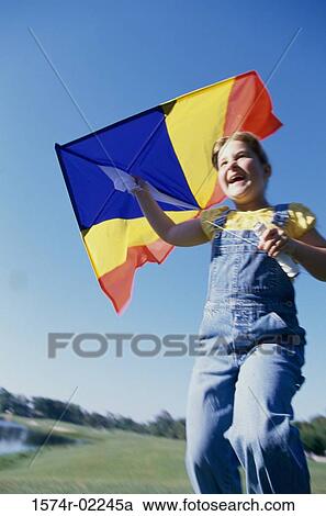 Low angle view of a girl holding a kite View Large Photo Image Stock Image - Low angle view of a girl holding a kite. Fotosearch