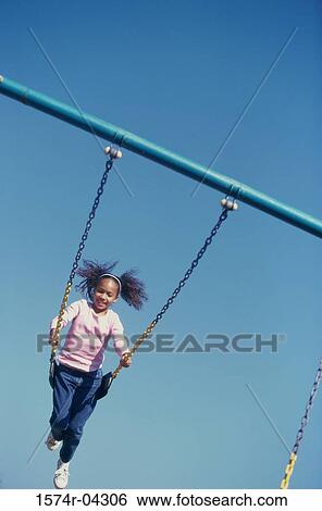 Low angle view of a girl swinging on a swing View Large Photo Image Stock Photograph - Low angle view of a girl swinging on a swing. Fotosearch
