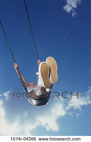 Low angle view of a girl swinging on a swing View Large Photo Image Stock Photograph - Low angle view of a girl swinging on a swing. Fotosearch