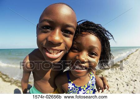 Stock Image - Portrait of a boy and a girl playing on the beach. Fotosearch
