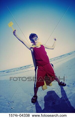 Portrait of a boy holding a shovel standing on the beach View Large Photo Image Stock Photo - Portrait of a boy holding a shovel standing on the beach. Fotosearch