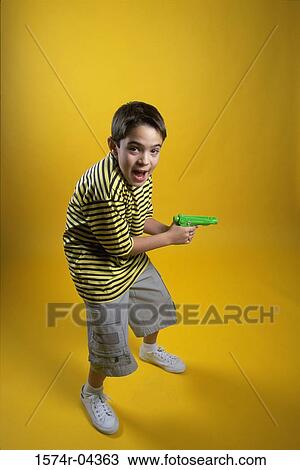 Stock Image - Portrait of a boy holding a squirt gun. Fotosearch
