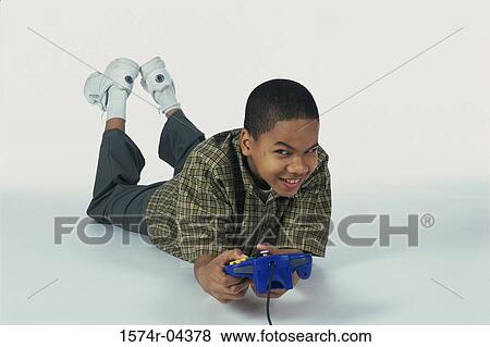 Portrait of a boy lying on the floor holding a game joystick View Large Photo Image Stock Photo - Portrait of a boy lying on the floor holding a game joystick. Fotosearch