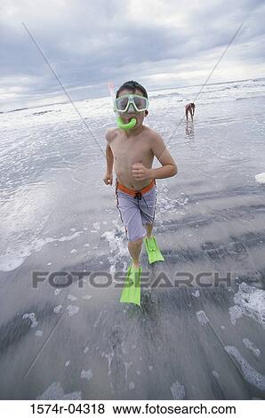 Stock Photo - Portrait of a boy wearing a snorkel running on the beach. Fotosearch