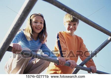 Stock Image - Portrait of a girl and a boy on monkey bars. Fotosearch
