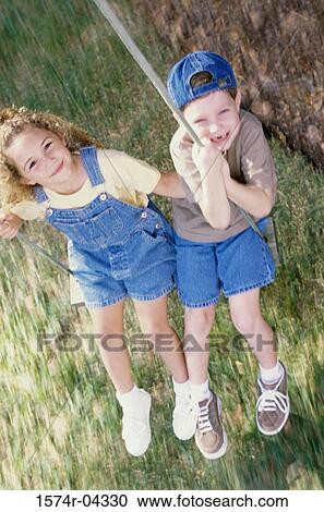 Portrait of a girl and a boy sitting on a swing View Large Photo Image Stock Image - Portrait of a girl and a boy sitting on a swing. Fotosearch
