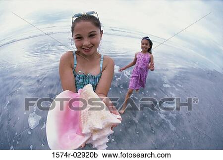 Stock Image - Portrait of a girl holding a conch shell. Fotosearch