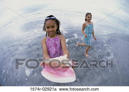 Stock Image - Portrait of a girl holding a conch shell. Fotosearch