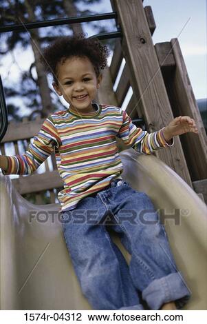 Stock Image - Portrait of a girl sliding down a slide. Fotosearch