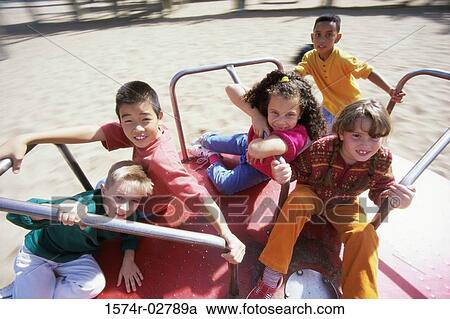 Stock Image - Portrait of a group of children sitting on a merry-go-round. Fotosearch
