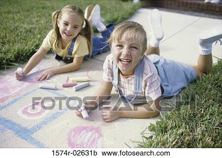 Portrait of two girls drawing on the ground with chalk View Large Photo Image Stock Image - Portrait of two girls drawing on the ground with chalk. Fotosearch