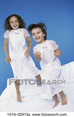 Portrait of two girls jumping on a bed View Large Photo Image Stock Image - Portrait of two girls jumping on a bed. Fotosearch