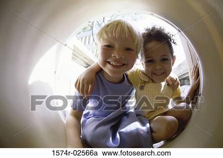Portrait of two girls playing in a tube View Large Photo Image Stock Image - Portrait of two girls playing in a tube. Fotosearch