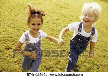 Stock Image - Portrait of two girls walking together on a lawn. Fotosearch