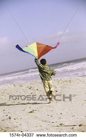 Stock Photo - Rear view of a boy flying a kite on the beach. Fotosearch