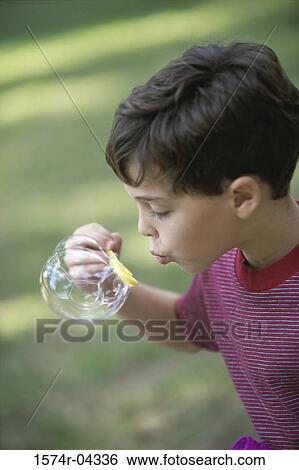 Stock Photograph - Side profile of a boy blowing bubbles. Fotosearch