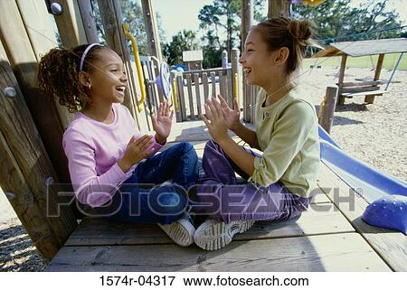 Stock Photo - Side profile of two girls playing the clapping game. Fotosearch