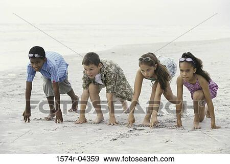 Stock Photo - Two boys and two girls at starting positions on the beach. Fotosearch