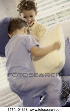 Two boys having a pillow fight on a bed View Large Photo Image Stock Image - Two boys having a pillow fight on a bed. Fotosearch