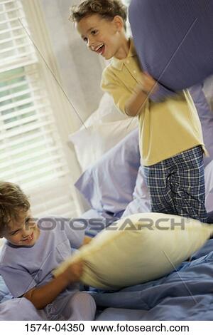 Two boys having a pillow fight on a bed View Large Photo Image Stock Image - Two boys having a pillow fight on a bed. Fotosearch
