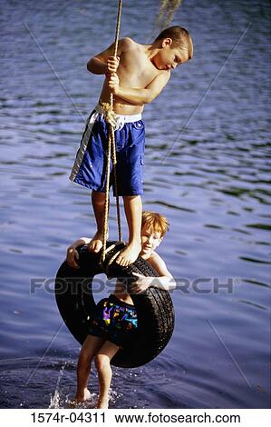 Two boys playing on a tire swing View Large Photo Image Stock Image - Two boys playing on a tire swing. Fotosearch