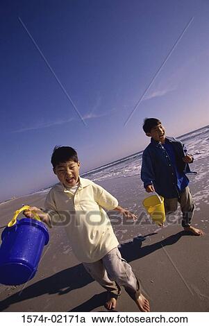 Two boys running with sand pails on the beach View Large Photo Image Stock Image - Two boys running with sand pails on the beach. Fotosearch
