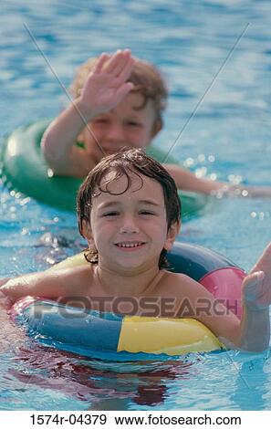 Stock Photo - Two boys wearing inner tubes in a swimming pool. Fotosearch