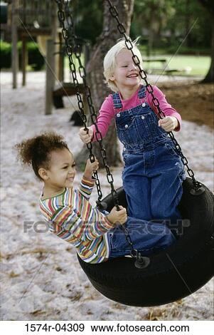 Stock Photo - Two girls playing on a swing. Fotosearch