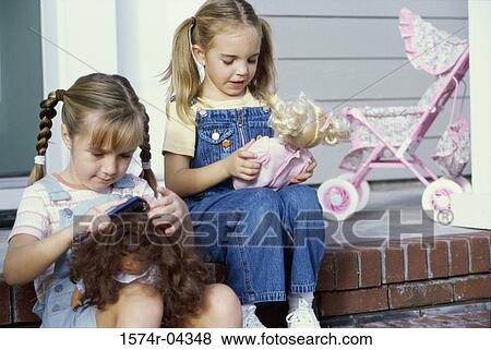 Two girls sitting together with their dolls View Large Photo Image Stock Photo - Two girls sitting together with their dolls. Fotosearch