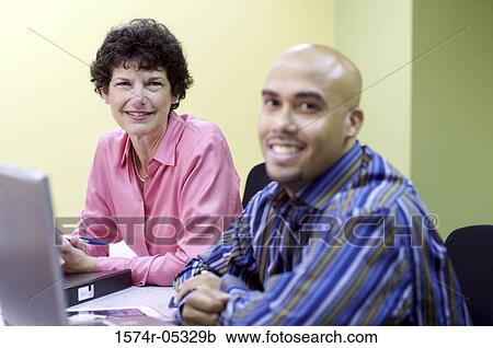 Portrait of a businessman and a businesswoman sitting in a conference room View Large Photo Image Stock Image - Portrait of a businessman and a businesswoman sitting in a conference room. Fotosearch