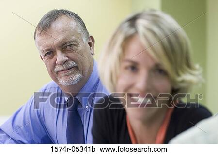 Portrait of a businessman and a businesswoman sitting in a conference room View Large Photo Image Stock Image - Portrait of a businessman and a businesswoman sitting in a conference room. Fotosearch