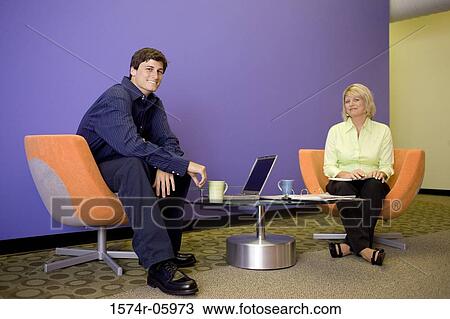 Stock Image - Portrait of a businessman and a businesswoman sitting in an office. Fotosearch