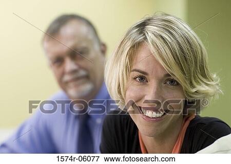 Stock Photo - Portrait of a businessman and a businesswoman sitting in a conference room. Fotosearch