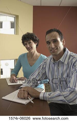 Portrait of a businessman and a businesswoman sitting in a conference room View Large Photo Image Stock Photograph - Portrait of a businessman and a businesswoman sitting in a conference room. Fotosearch