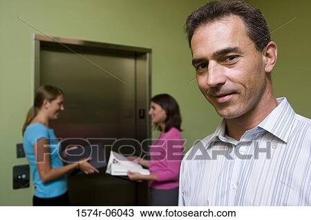 Portrait of a businessman and two businesswomen standing behind him View Large Photo Image Stock Image - Portrait of a businessman and two businesswomen standing behind him. Fotosearch